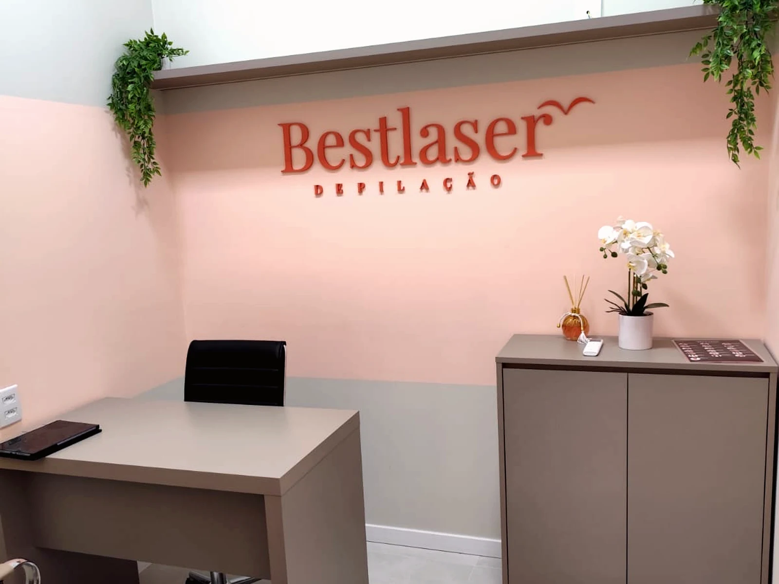 Ambiente real da Bestlaser com mesa de atendimento e marca na parede salmão.